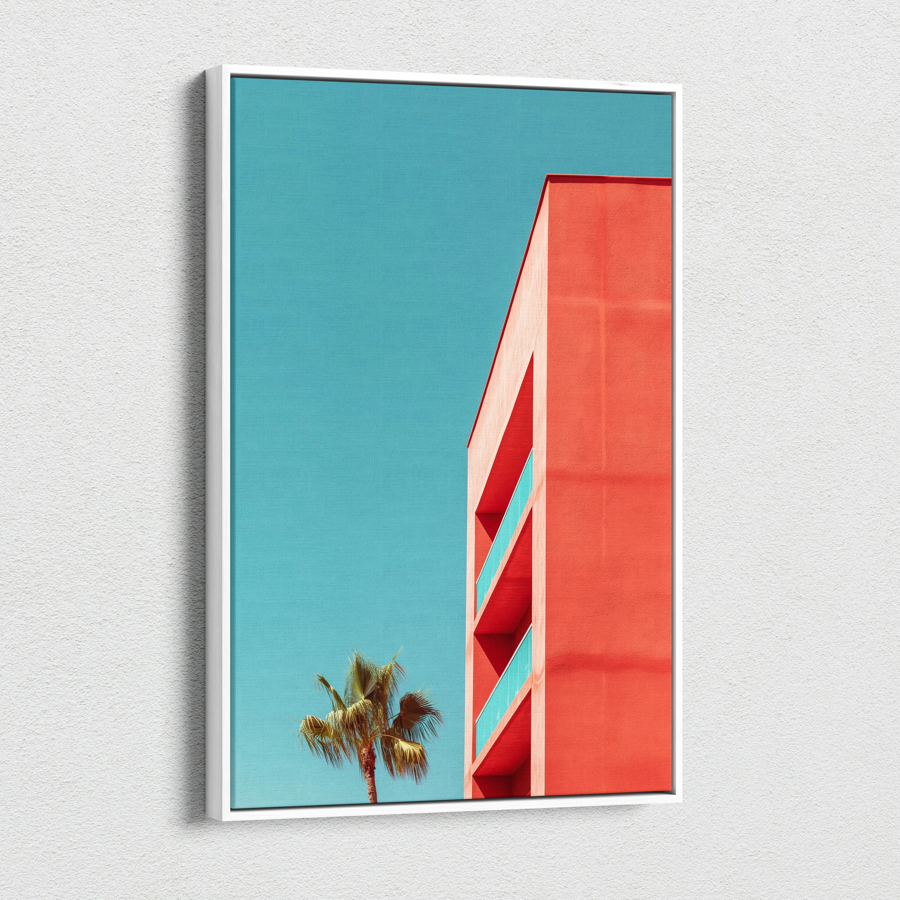 Vertical canvas wall art featuring modern red building architecture against a clear blue sky with a palm tree silhouette.