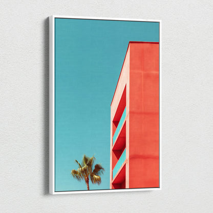 Vertical canvas wall art featuring modern red building architecture against a clear blue sky with a palm tree silhouette.