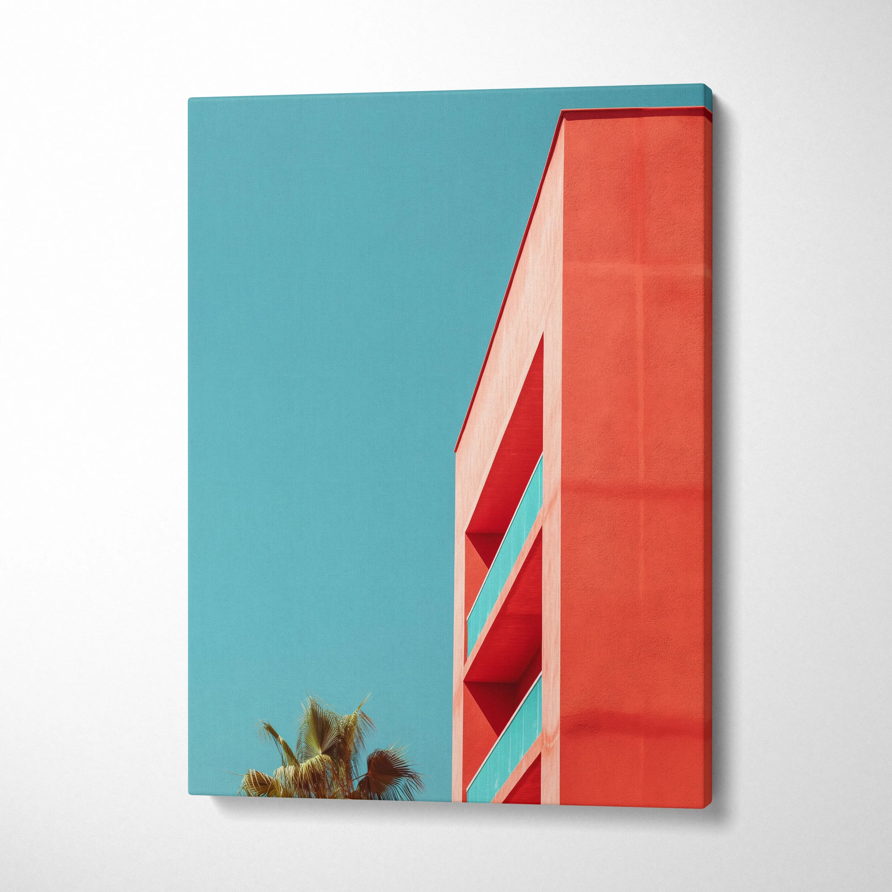 Vertical canvas wall art featuring modern red building architecture against a clear blue sky with palm trees.