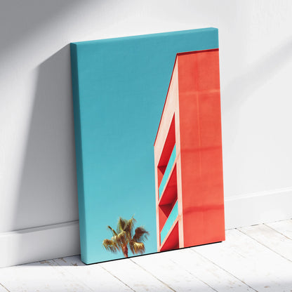 Vertical canvas wall art featuring modern red building against clear blue sky with palm tree silhouette.