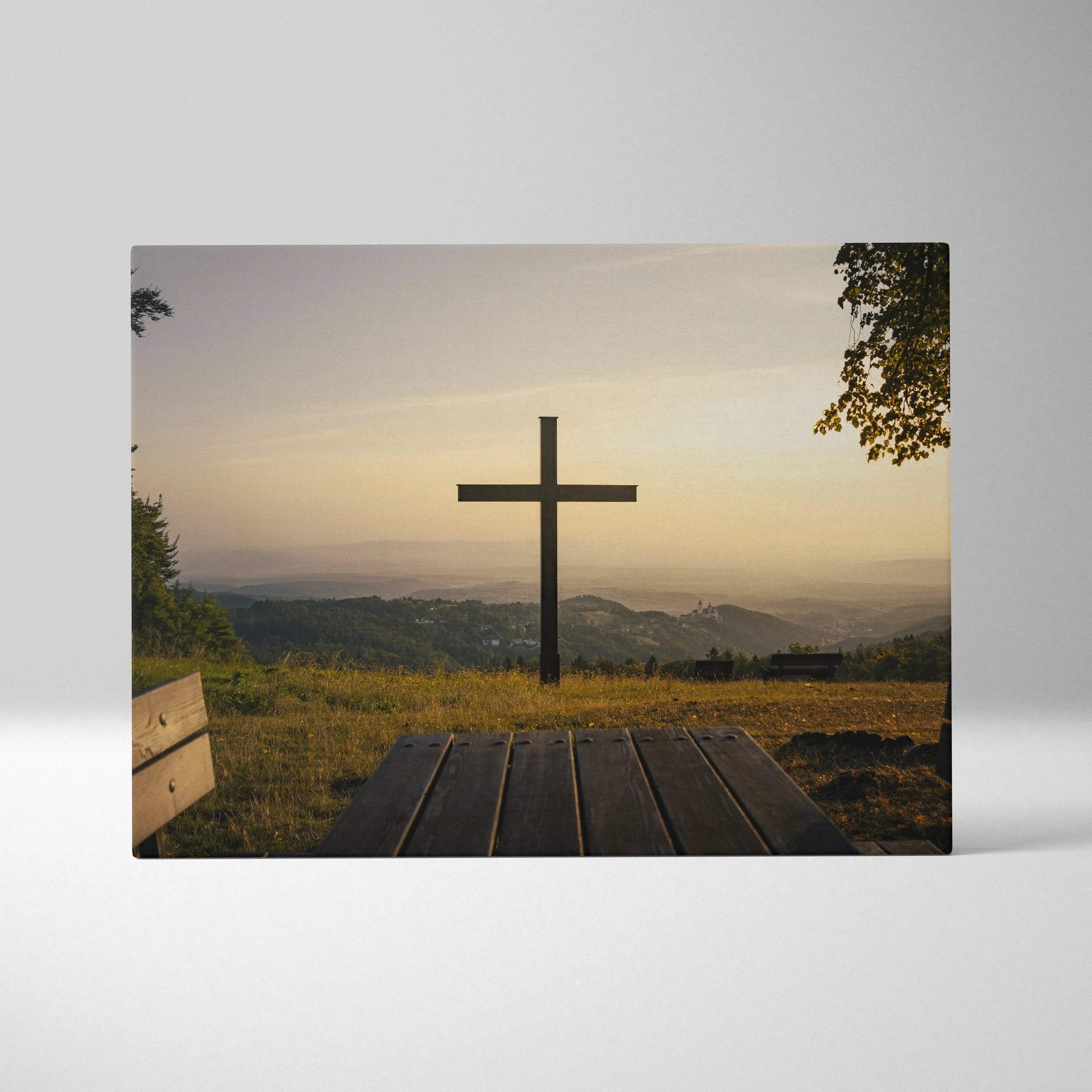 Canvas wall art featuring a wooden cross against a sunset sky over rolling hills and trees.