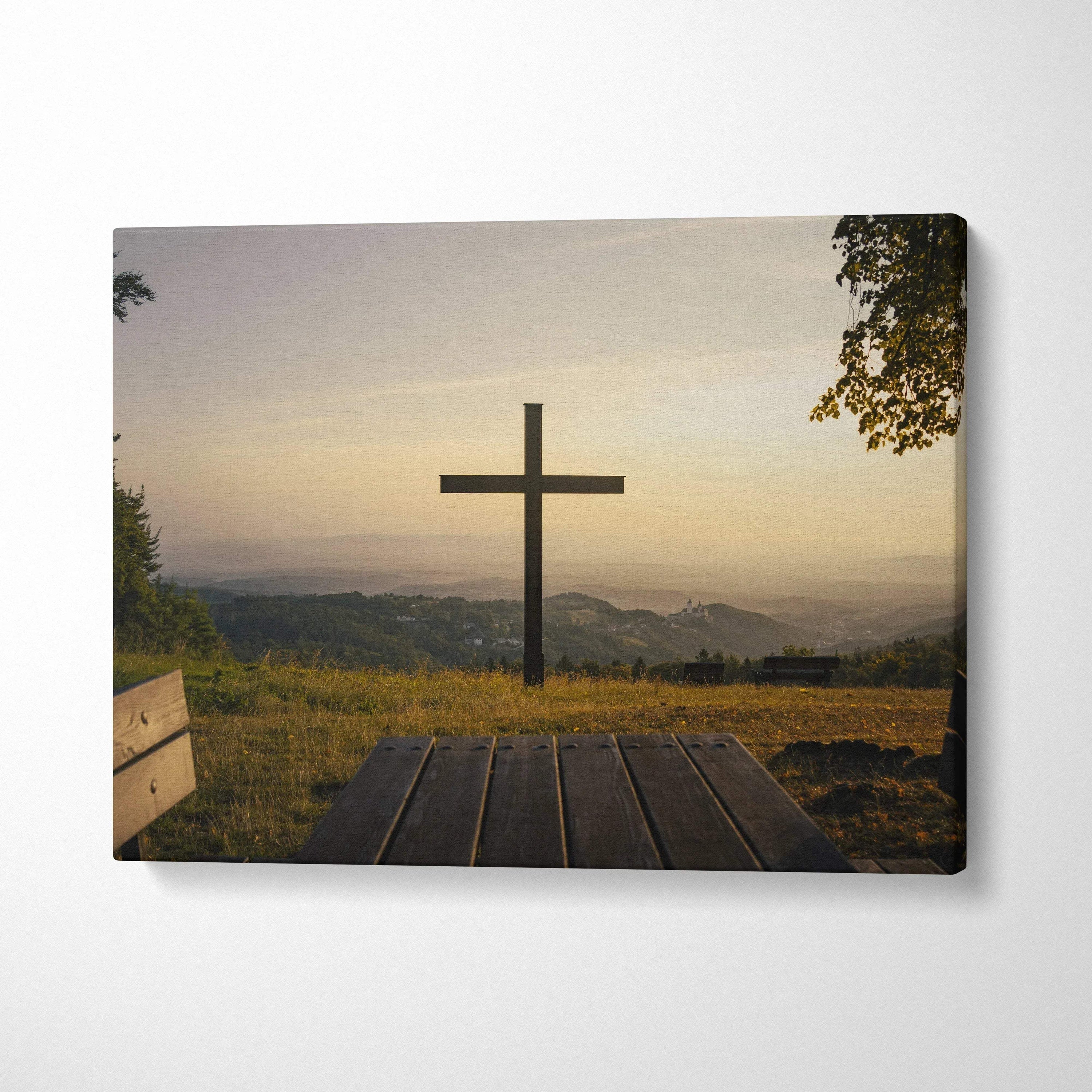 Canvas wall art featuring a wooden cross at sunset over grassy hills and distant mountains.