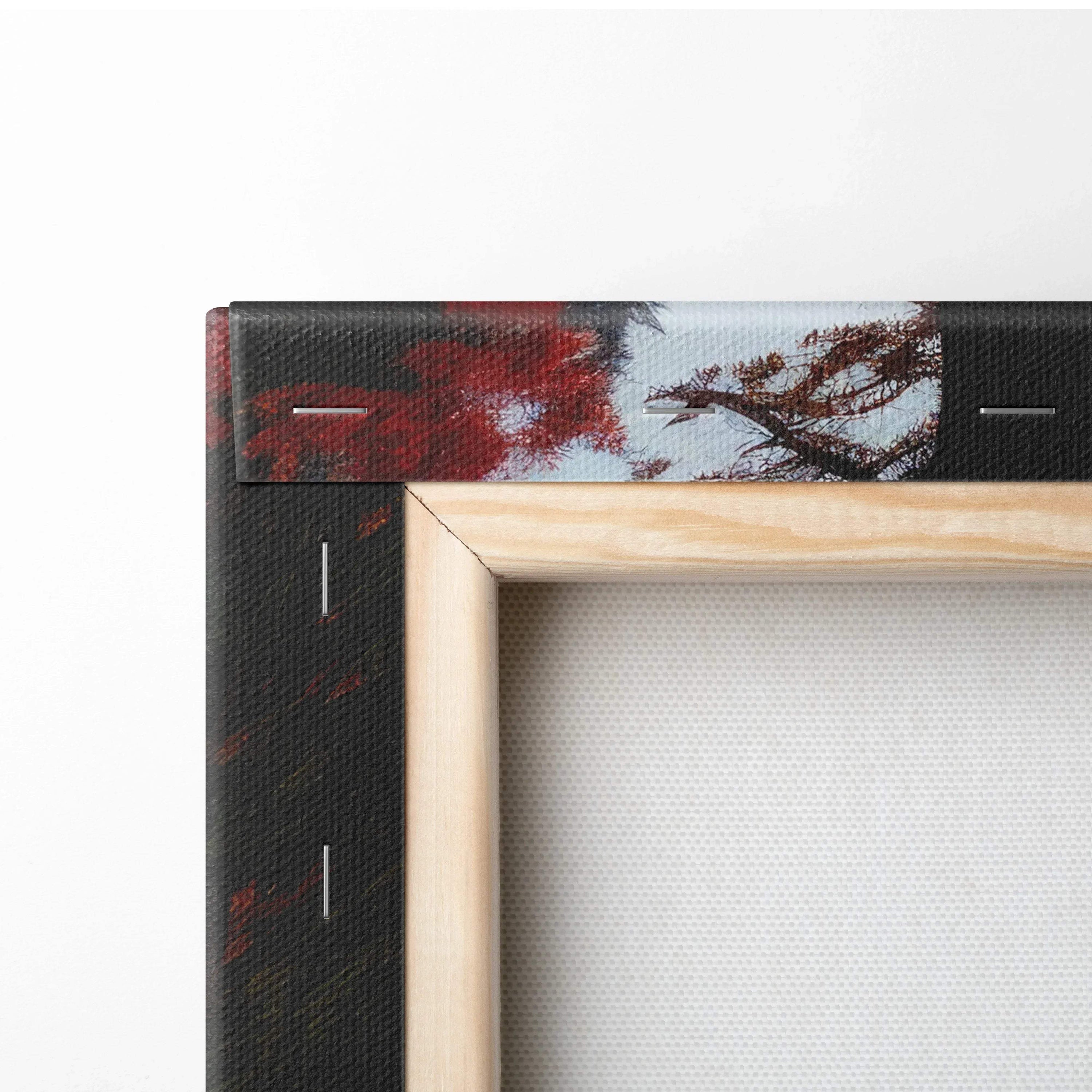Close-up of wooden frame corner and vibrant autumn leaves on canvas wall art with red, orange, and gold tones.