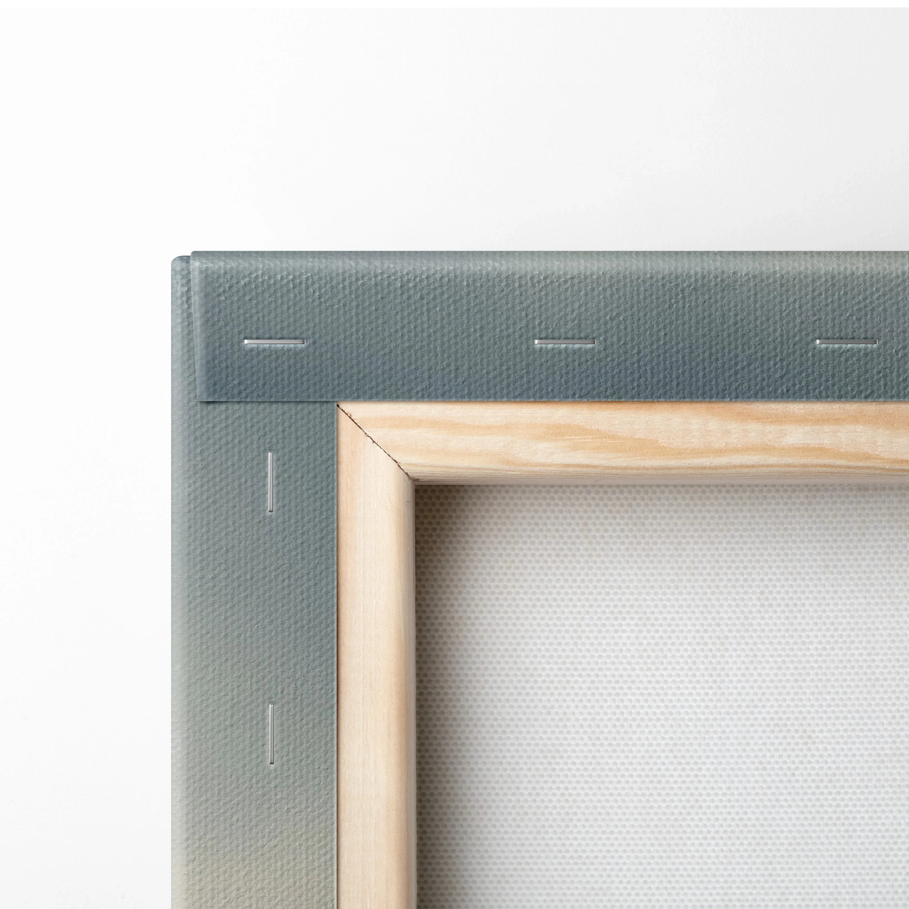 Close-up of wooden frame and stapled gray canvas fabric on vertical wall art canvas.