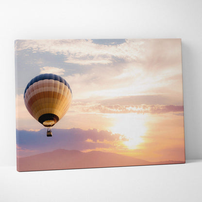 Sunset landscape hot air balloon canvas wall art with blue beige and gold stripes against a warm peach sky