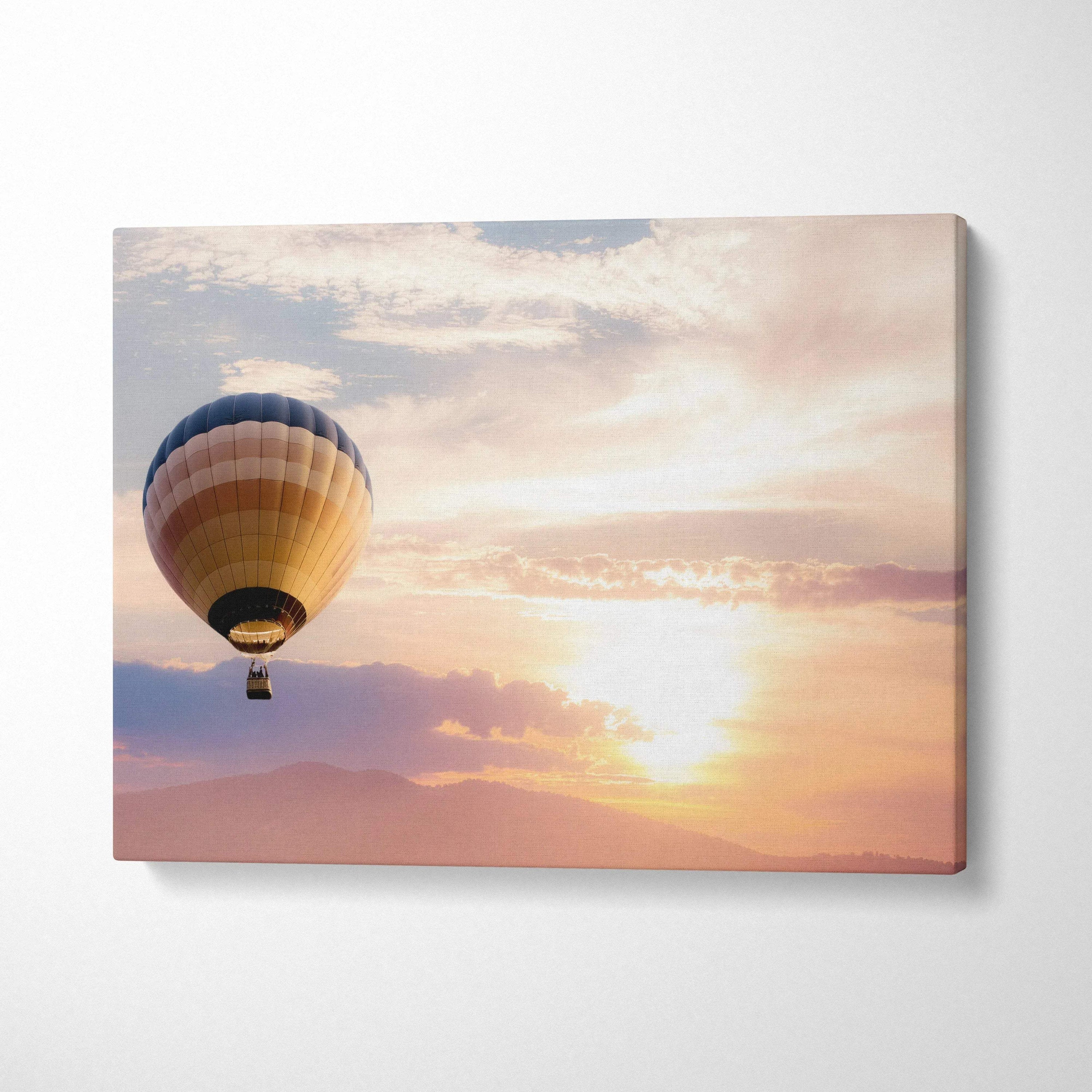 Sunset landscape hot air balloon canvas wall art featuring a blue beige and gold striped balloon against a peach sky