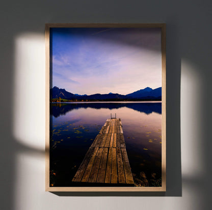 Vertical wall art poster featuring a wooden dock extending into a calm lake with mountain silhouettes at sunset.