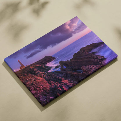 Canvas wall art featuring a tranquil beach sunset with rocky cliffs and a lighthouse under purple skies.