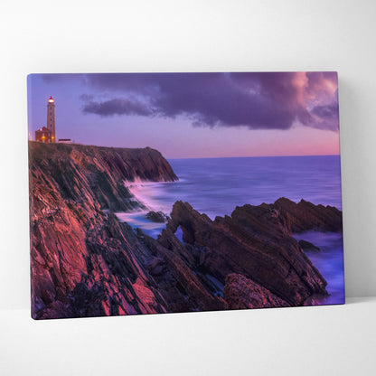 Canvas wall art featuring a tranquil beach sunset with rocky cliffs and a lighthouse under purple skies.