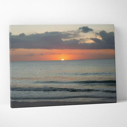 Canvas wall art featuring a vibrant sunset over a calm beach with gentle waves and clouds.