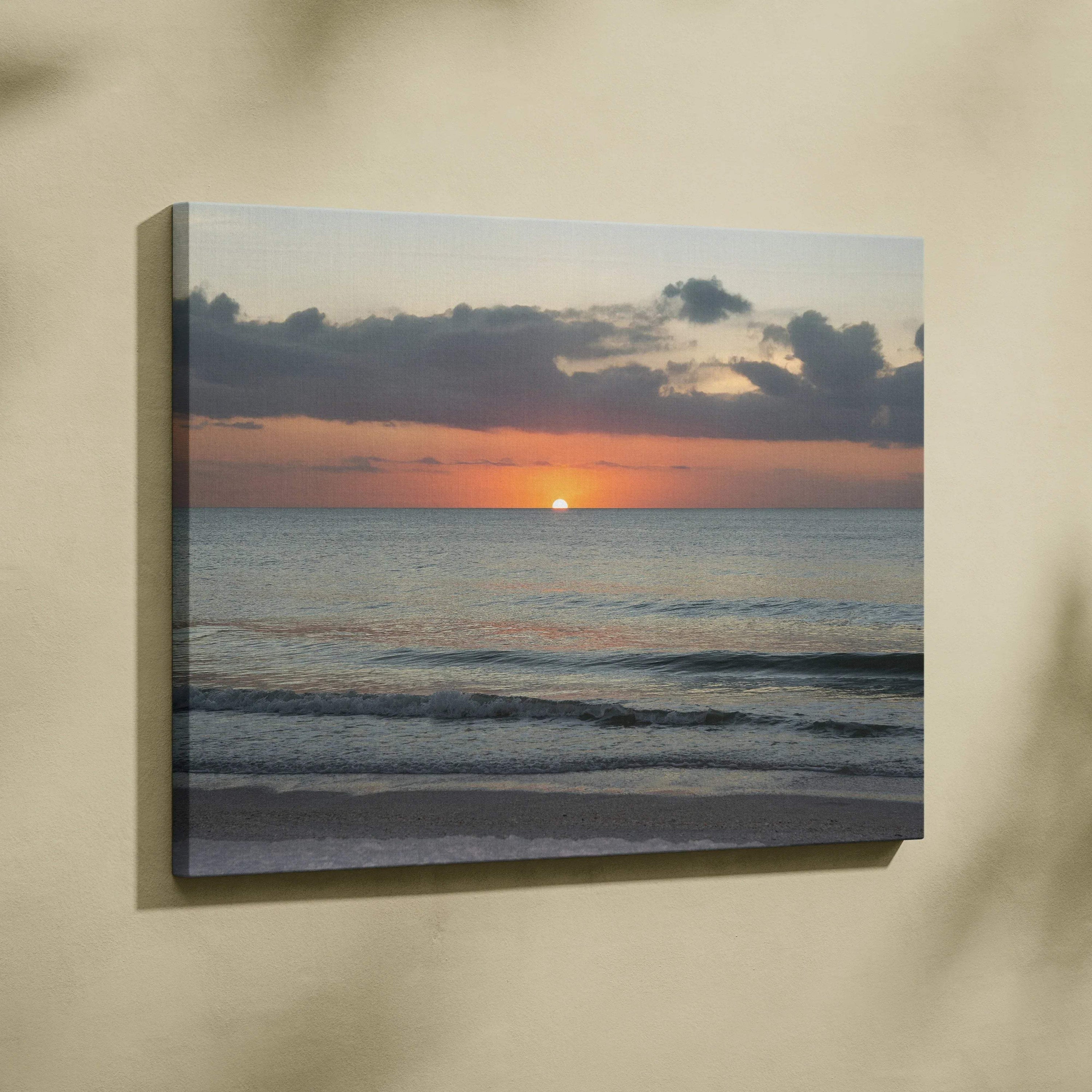 Canvas wall art featuring a vibrant sunset over a calm ocean with gentle waves and dark clouds.