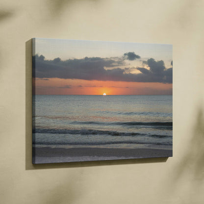 Canvas wall art featuring a vibrant sunset over a calm ocean with gentle waves and dark clouds.