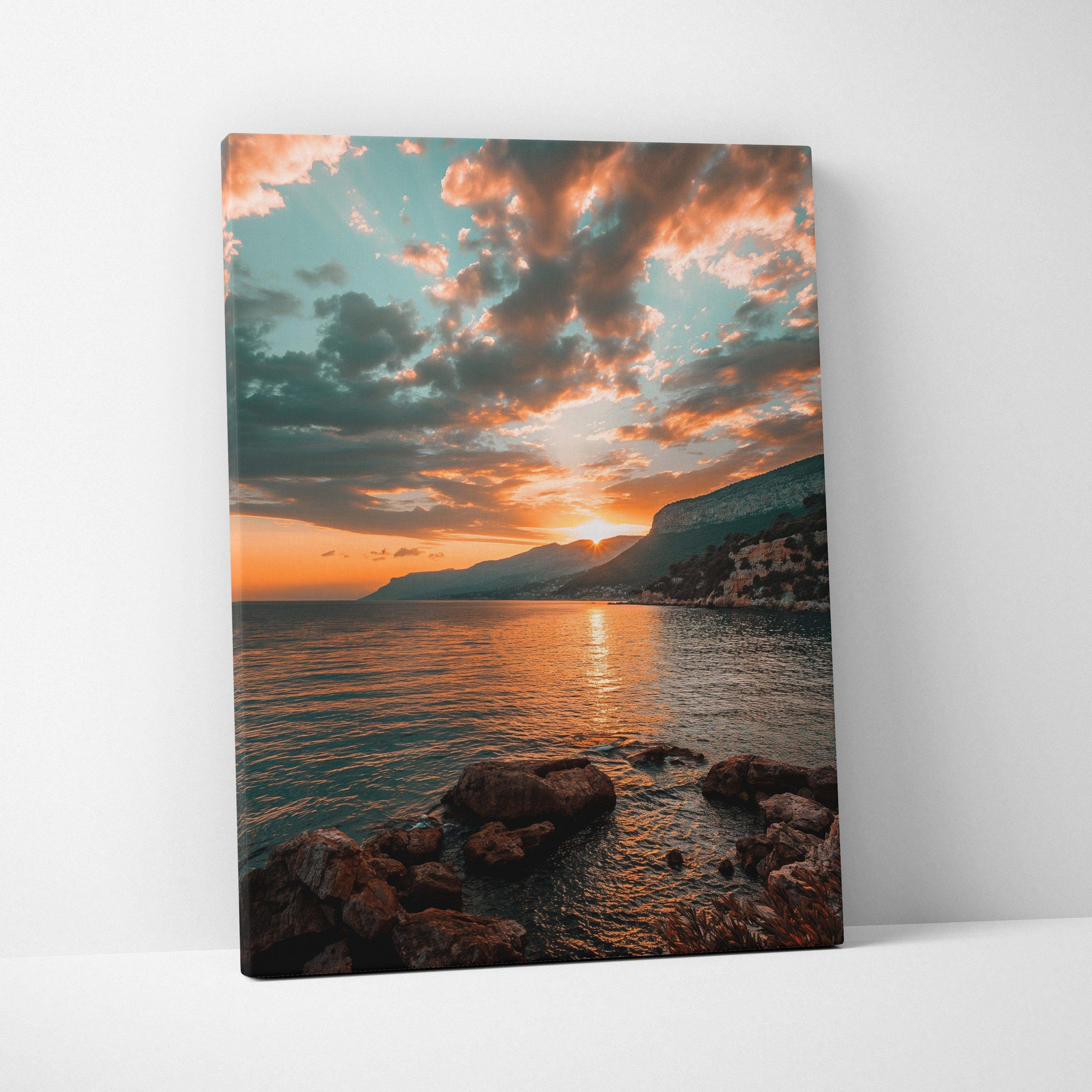 Canvas wall art featuring a sunset over mountains and rocky beach with dramatic clouds.