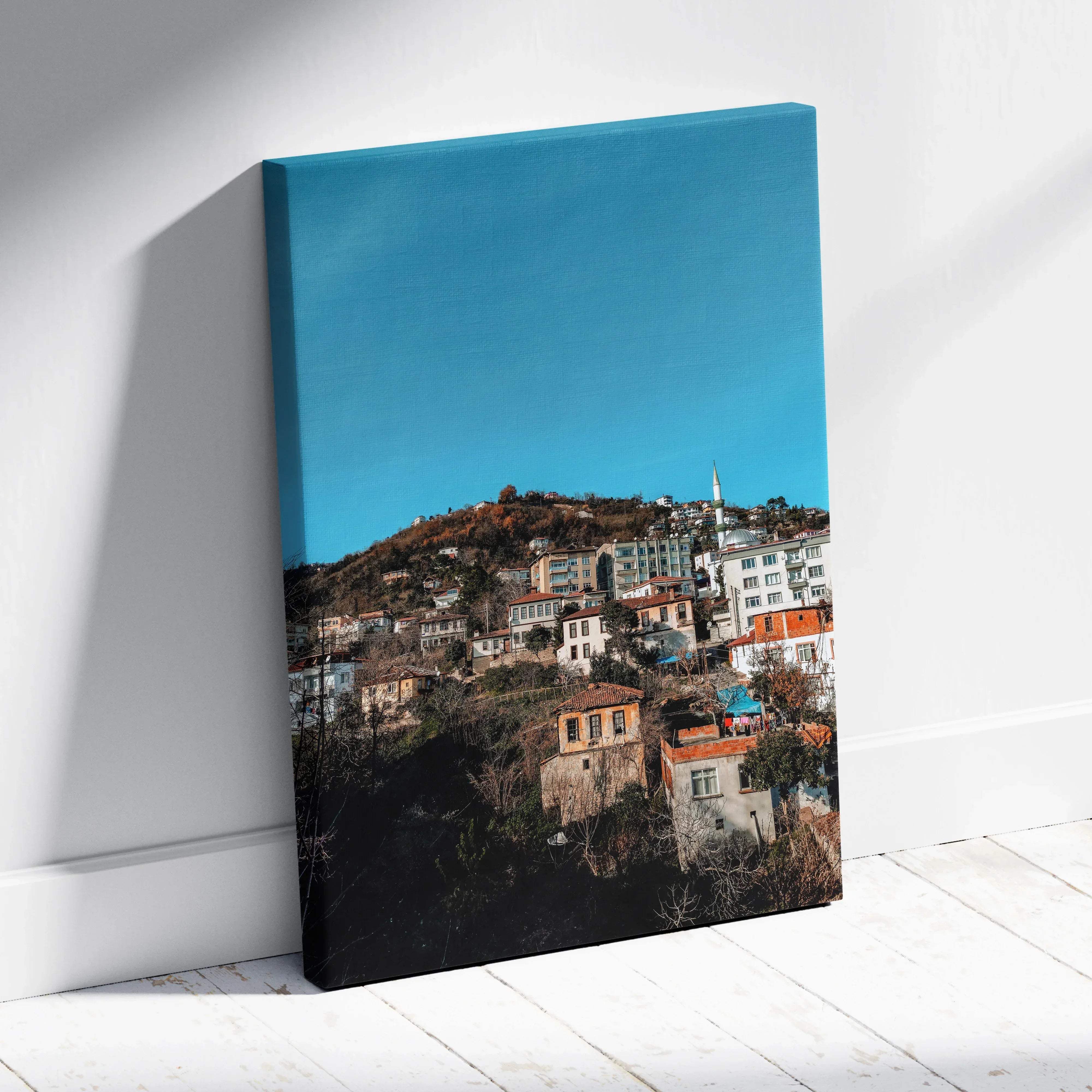 A vibrant canvas print of hillside town buildings with terracotta roofs under a bright turquoise sky for wall art