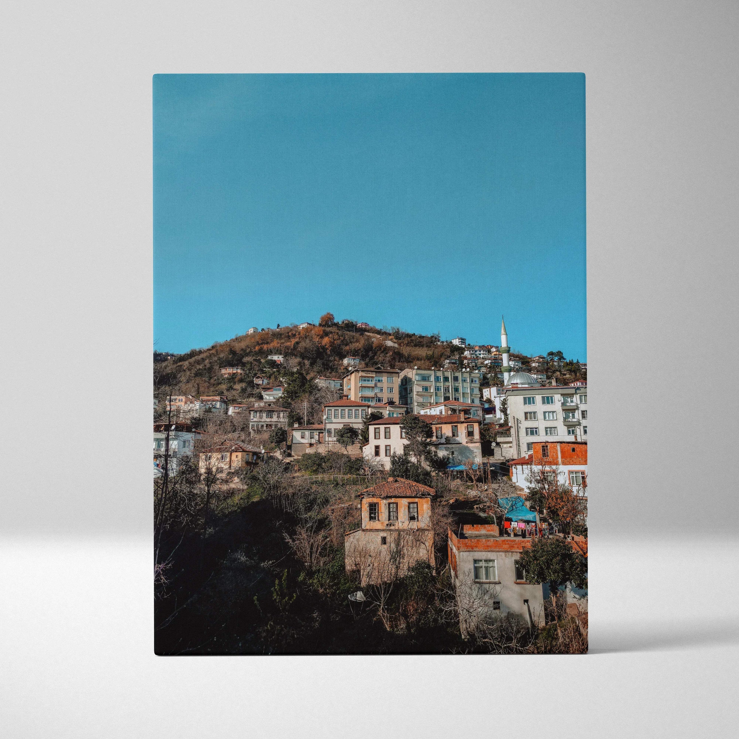 Vertical canvas wall art of colorful urban cityscape with buildings on hillside against blue sky.