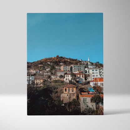 Vertical canvas wall art of colorful urban cityscape with buildings on hillside against blue sky.