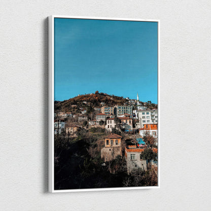 Vertical canvas wall art featuring a vibrant urban cityscape under a clear blue sky.
