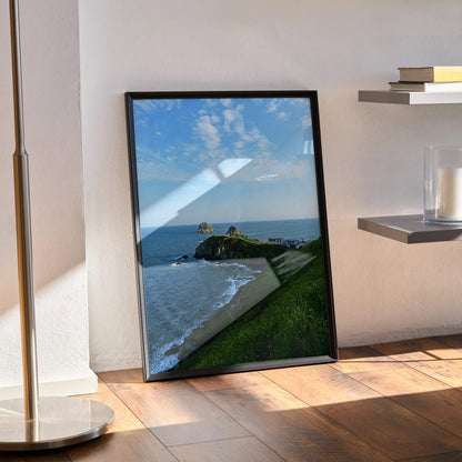 Ocean waves crashing on rocky coastline poster with blue sky wall art in black frame.