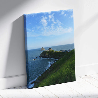 Vertical canvas wall art depicting tranquil beach and green mountains under a blue sky with scattered clouds.