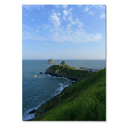 Vertical ocean waves art poster featuring rugged coastline with green cliffs under a blue sky wall art.