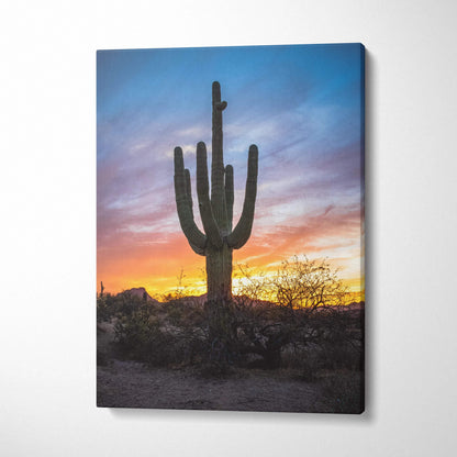 Vertical canvas wall art of a tall saguaro cactus silhouetted against a vibrant desert sunset sky.
