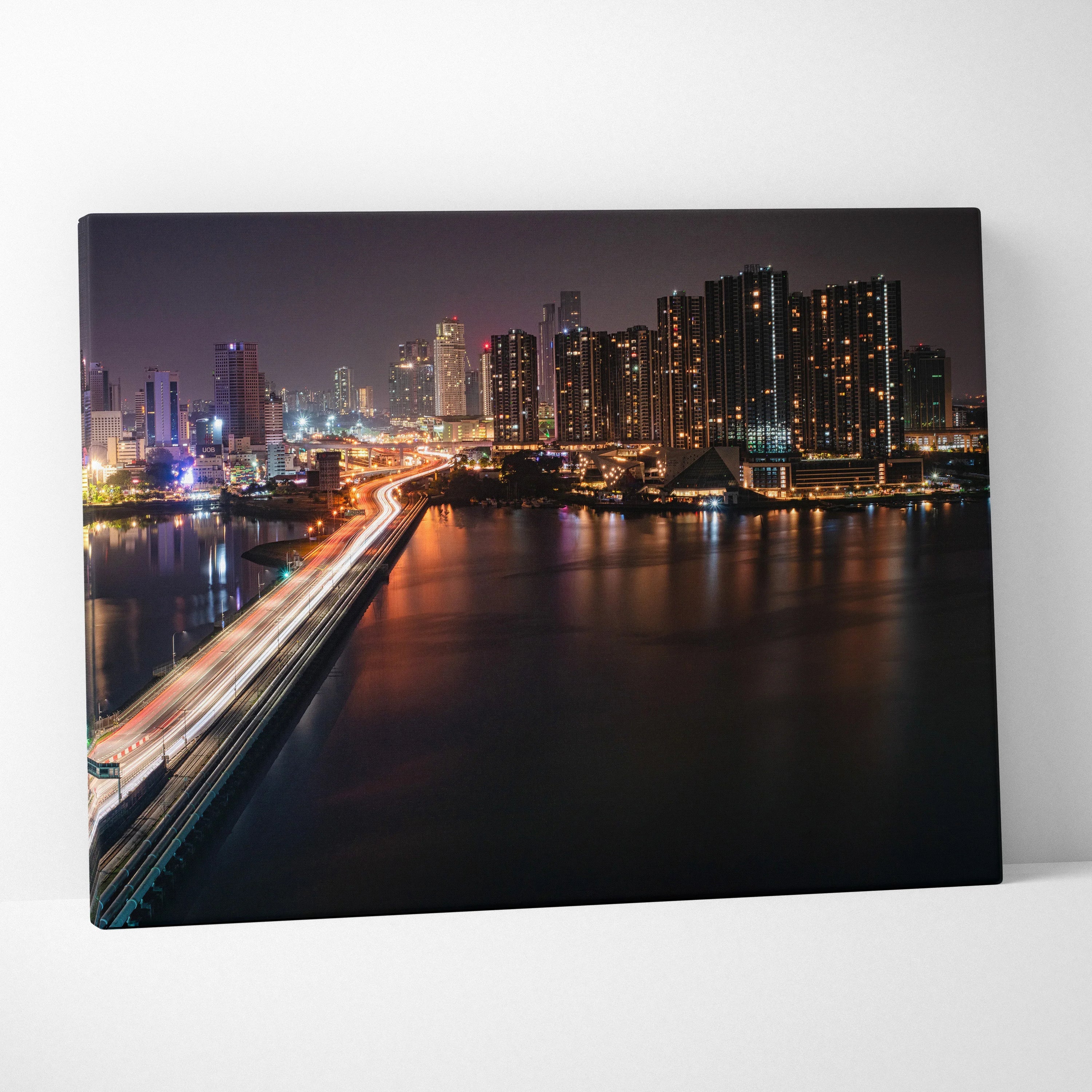 City skyline at night with illuminated buildings and bridge reflected on water canvas wall art.