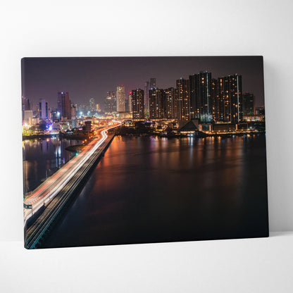 City skyline at night with illuminated buildings and bridge reflected on water canvas wall art.