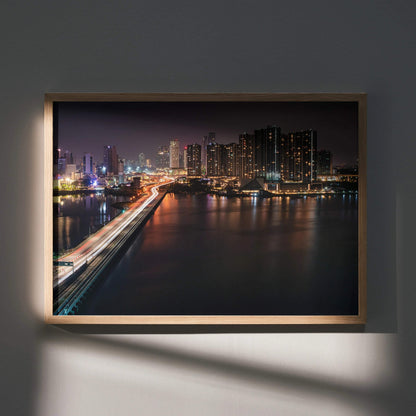 Vibrant city night skyline wall art poster with illuminated buildings and reflections on water, framed wooden wall art.