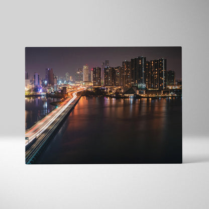 High-resolution canvas wall art featuring a night city skyline with illuminated buildings and bridge reflections on water.