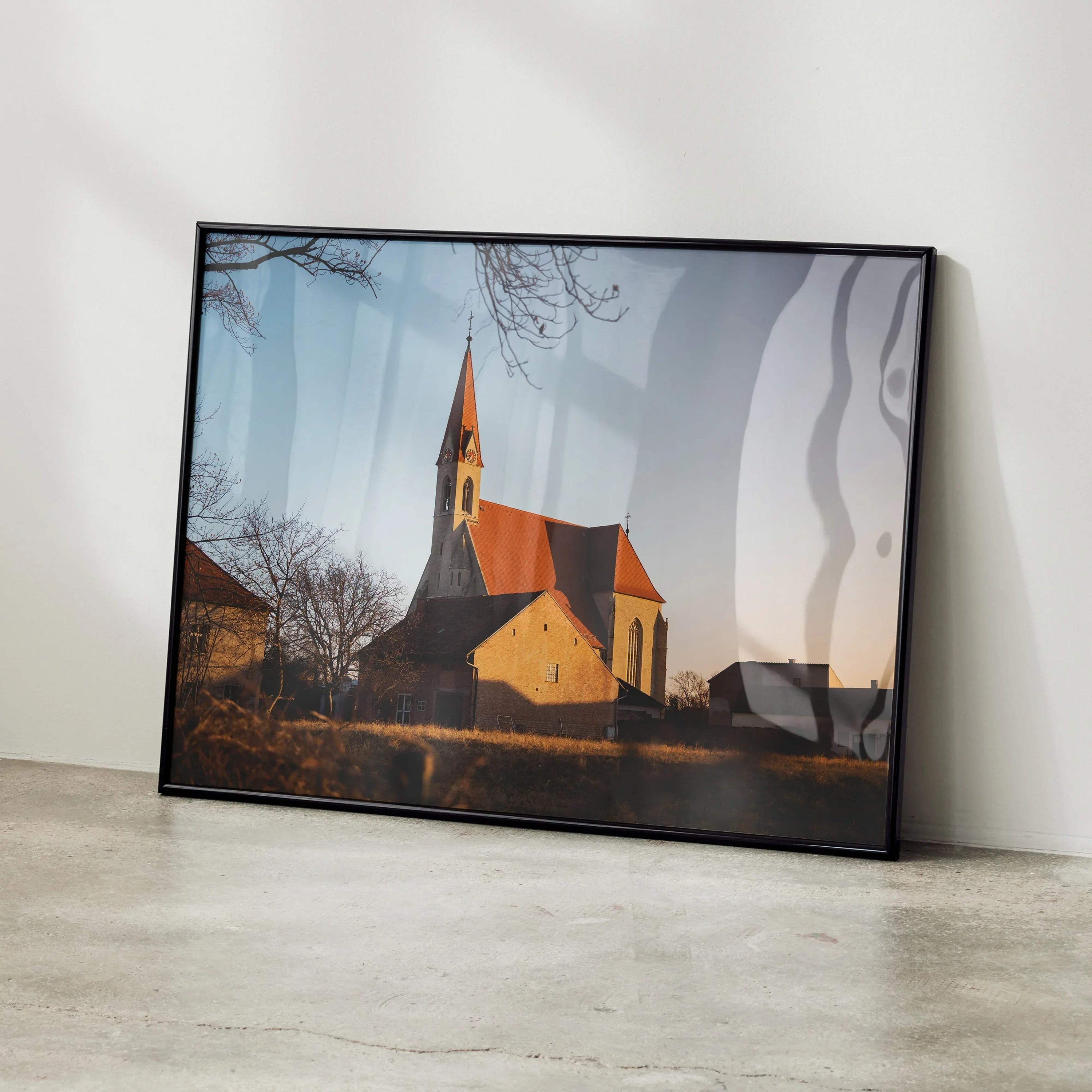 Framed poster wall art of serene church landscape at sunset with soft sky and bare trees.