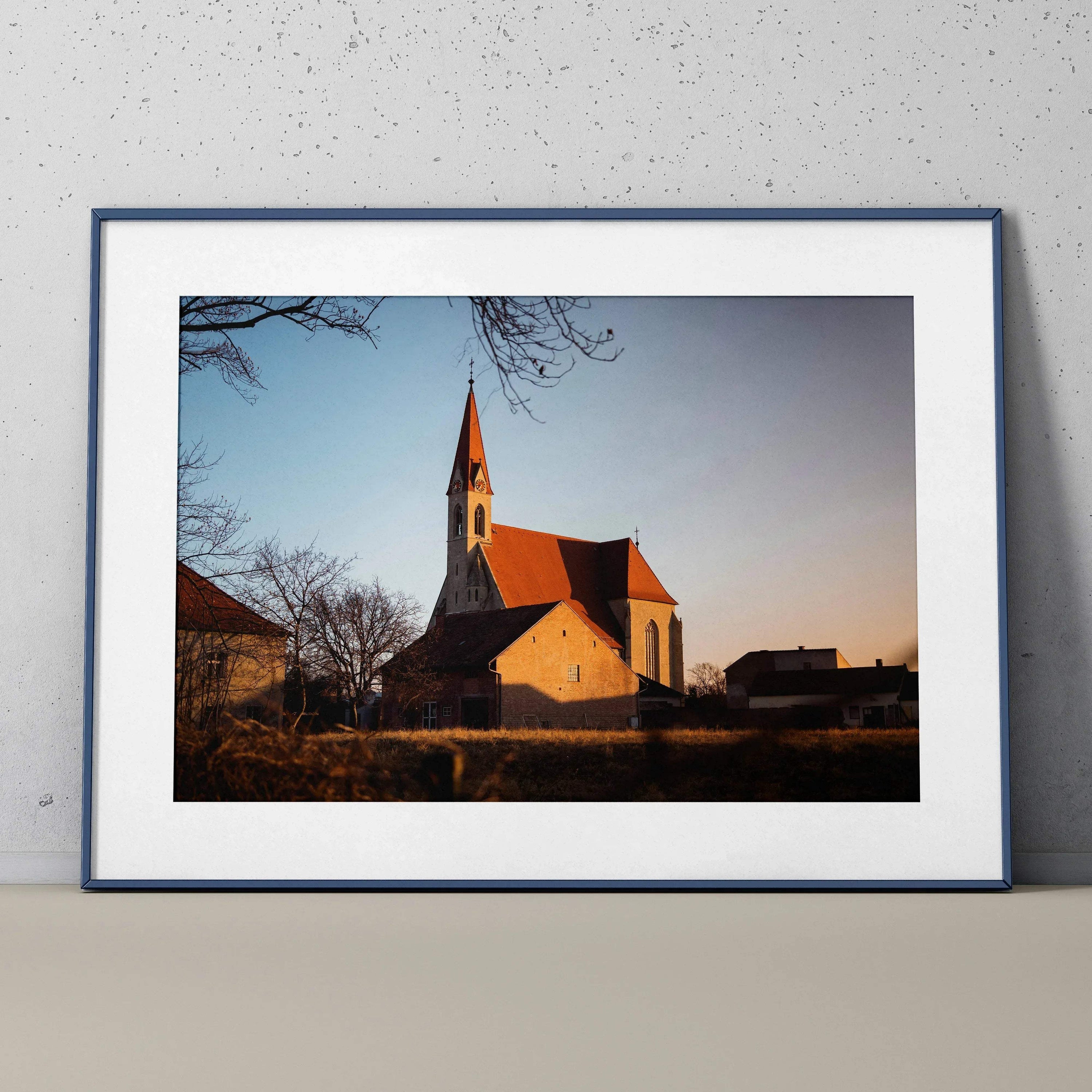 Serene church landscape at sunset wall art poster with blue sky and bare trees in white frame.