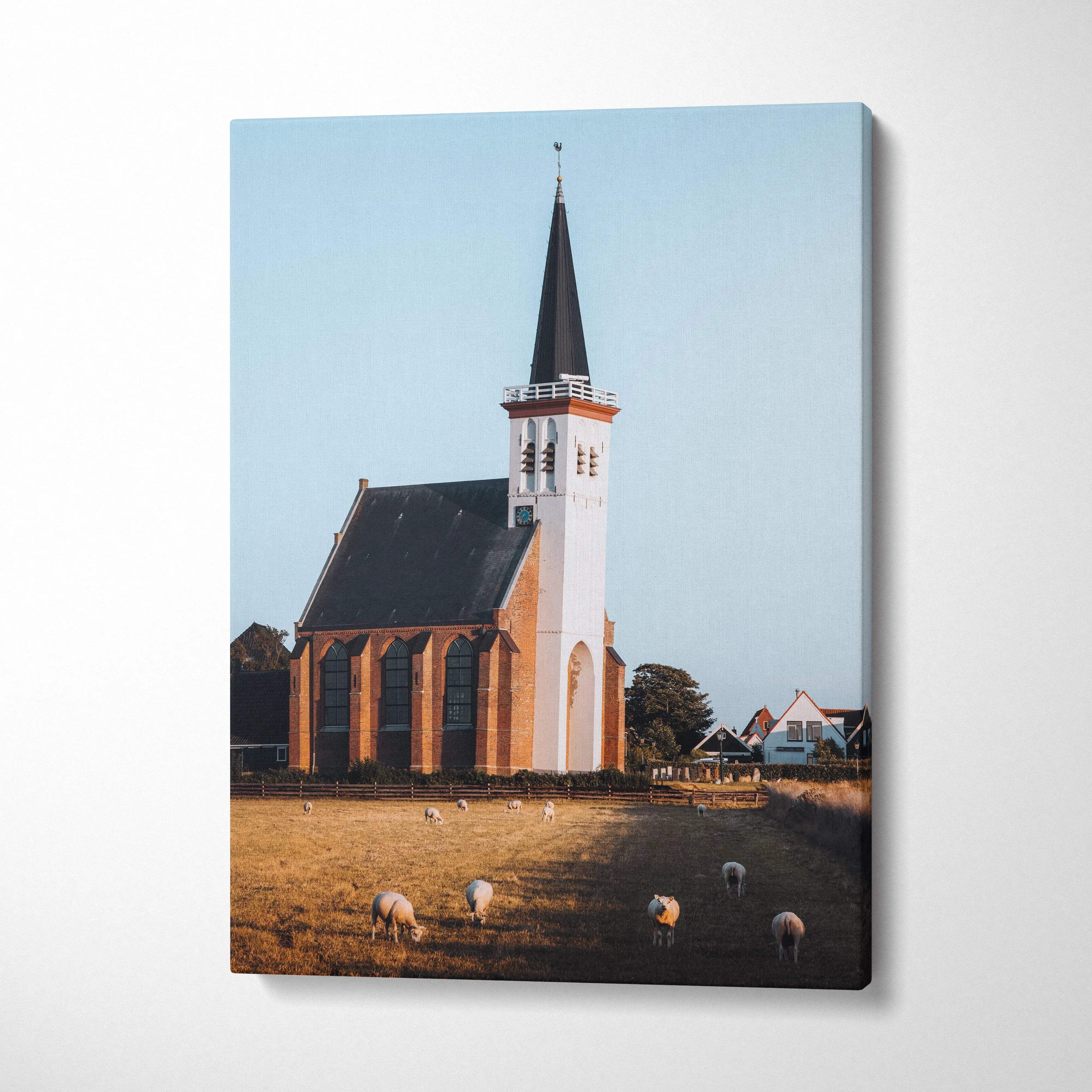 Canvas wall art print of an elegant church with a tall steeple and grazing sheep under a clear sky.