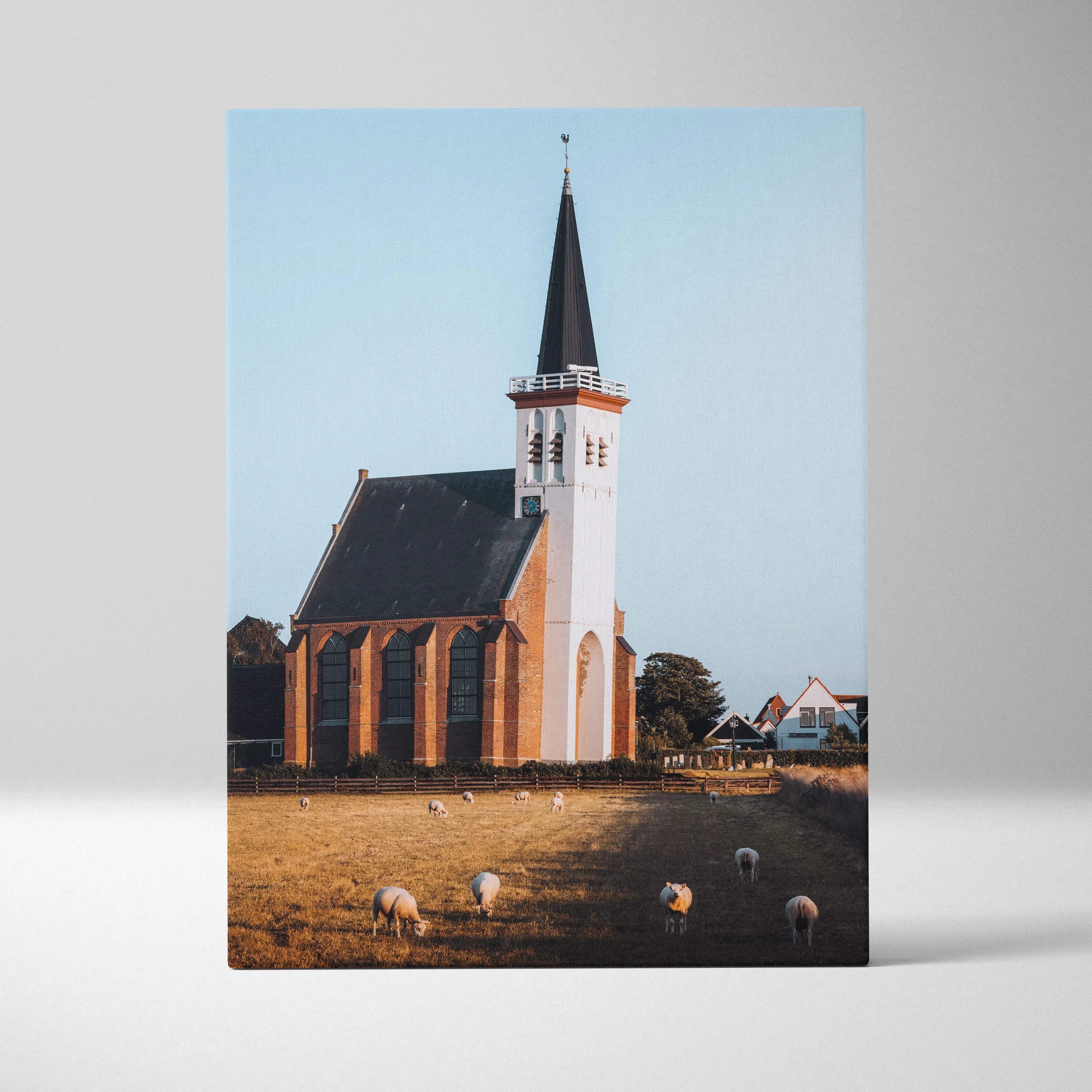 Vertical canvas wall art featuring a white church with a tall steeple against a clear blue sky.