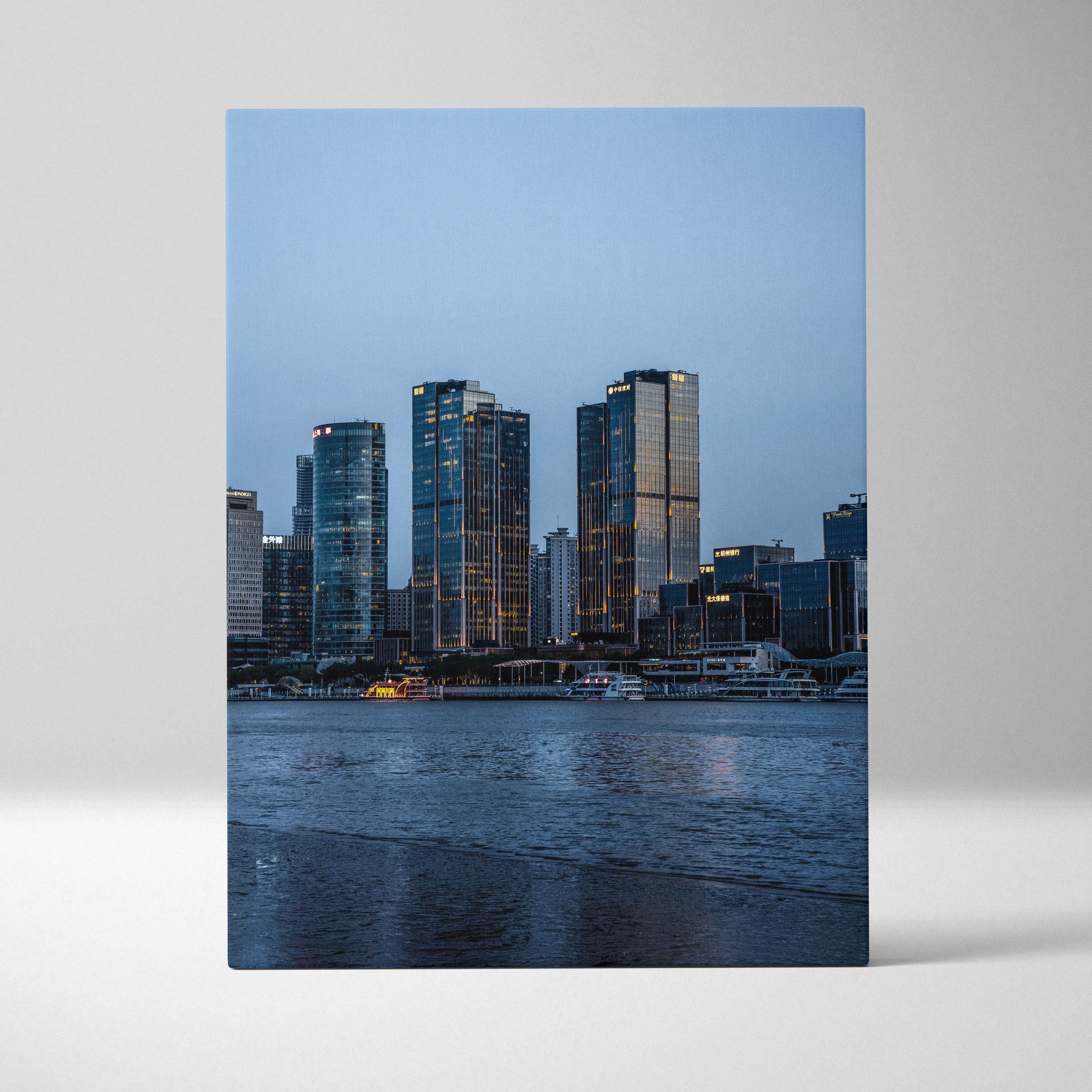 Vertical canvas wall art of a cityscape with illuminated modern buildings against a dusk sky.