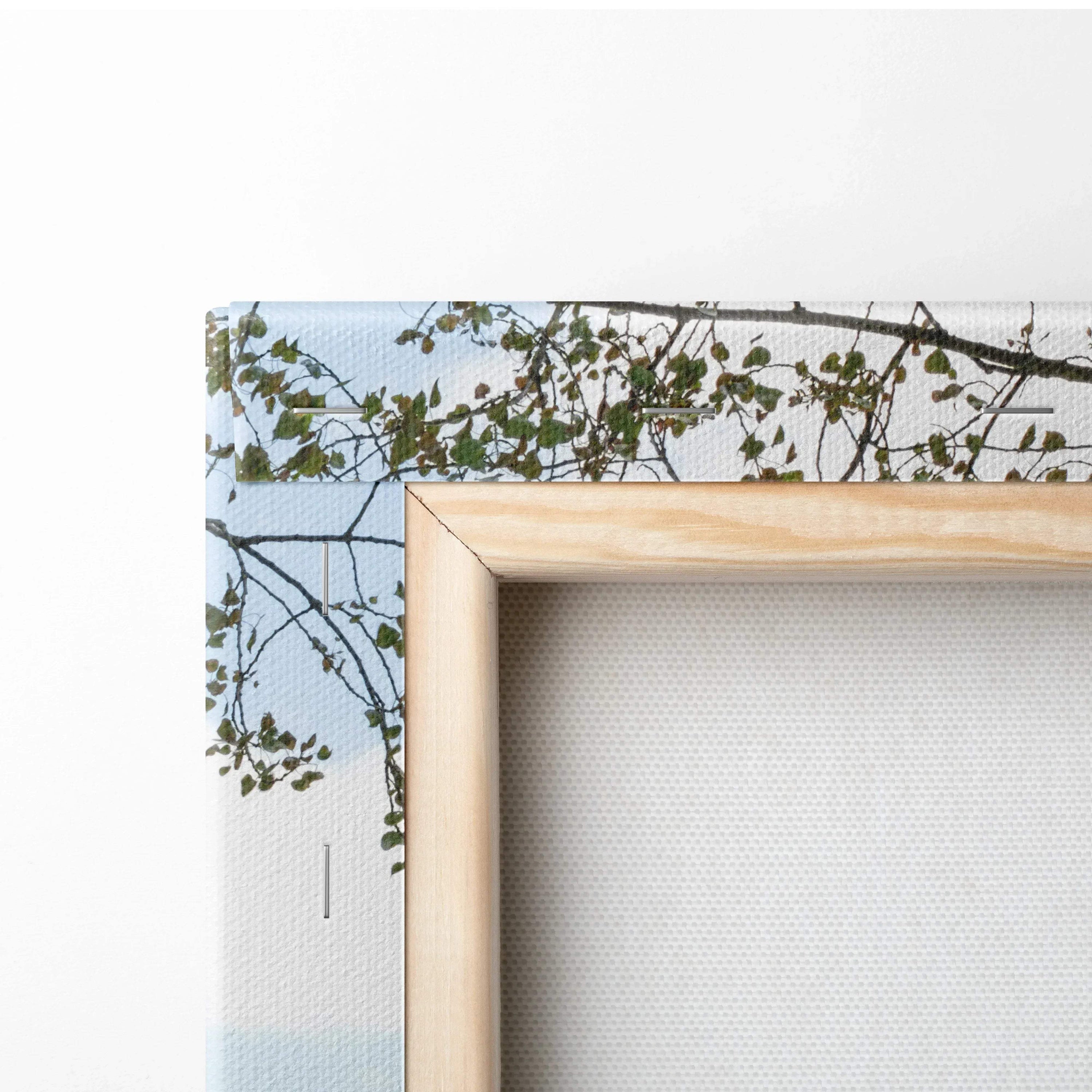 Close-up of wooden frame and edge of canvas wall art with detailed urban building and foliage print.
