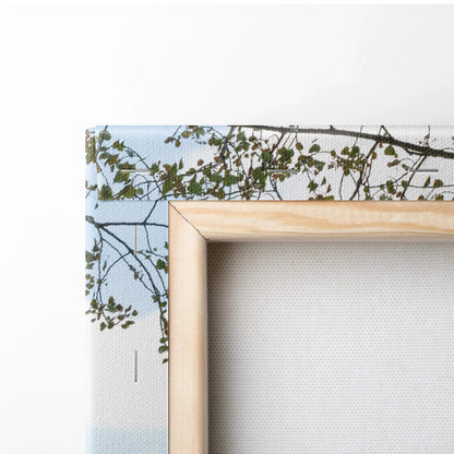 Close-up of wooden frame and edge of canvas wall art with detailed urban building and foliage print.