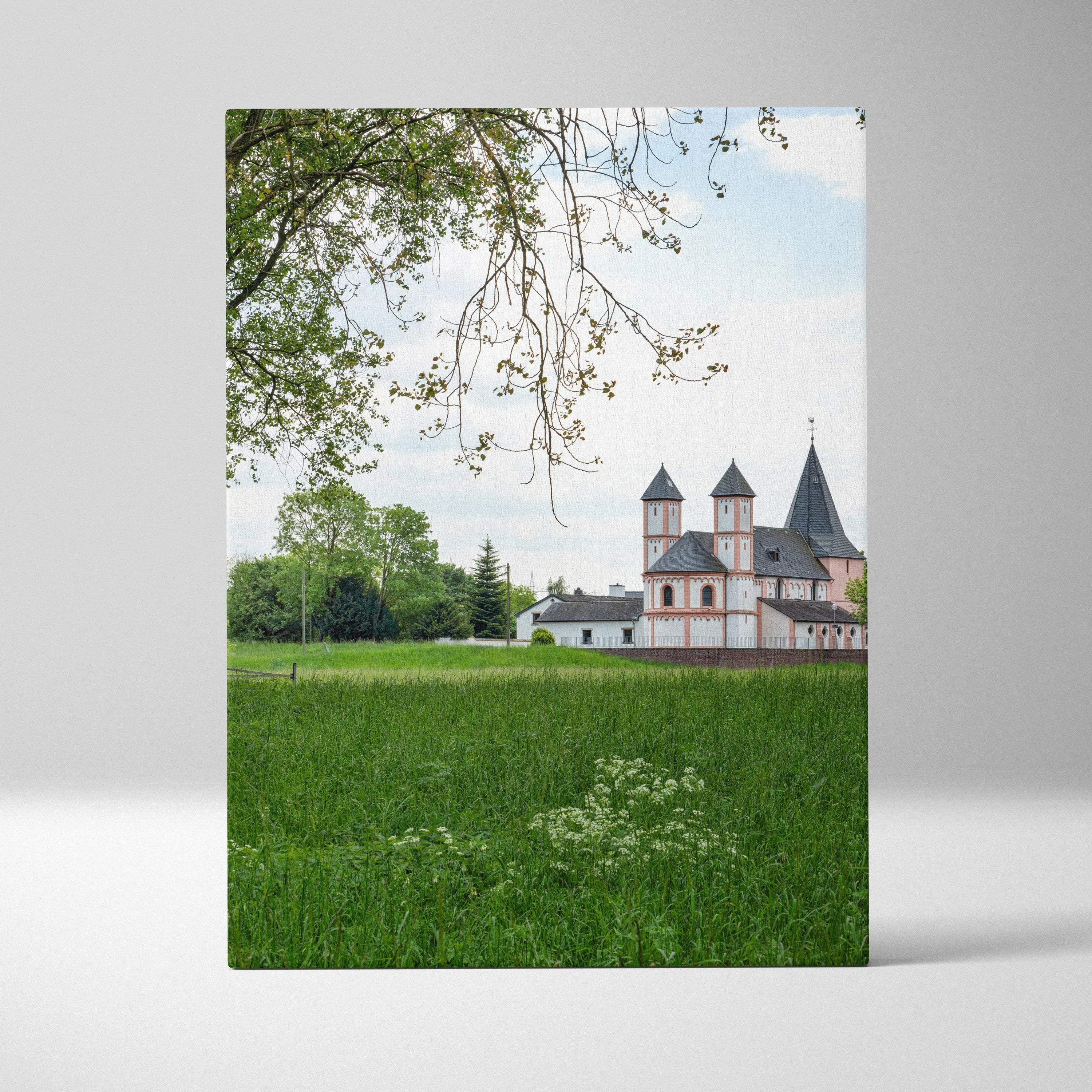 Canvas wall art featuring urban buildings with green field and tree branches in foreground.