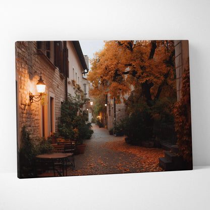 Autumn street scene canvas wall art with golden trees and rustic lights on buildings.