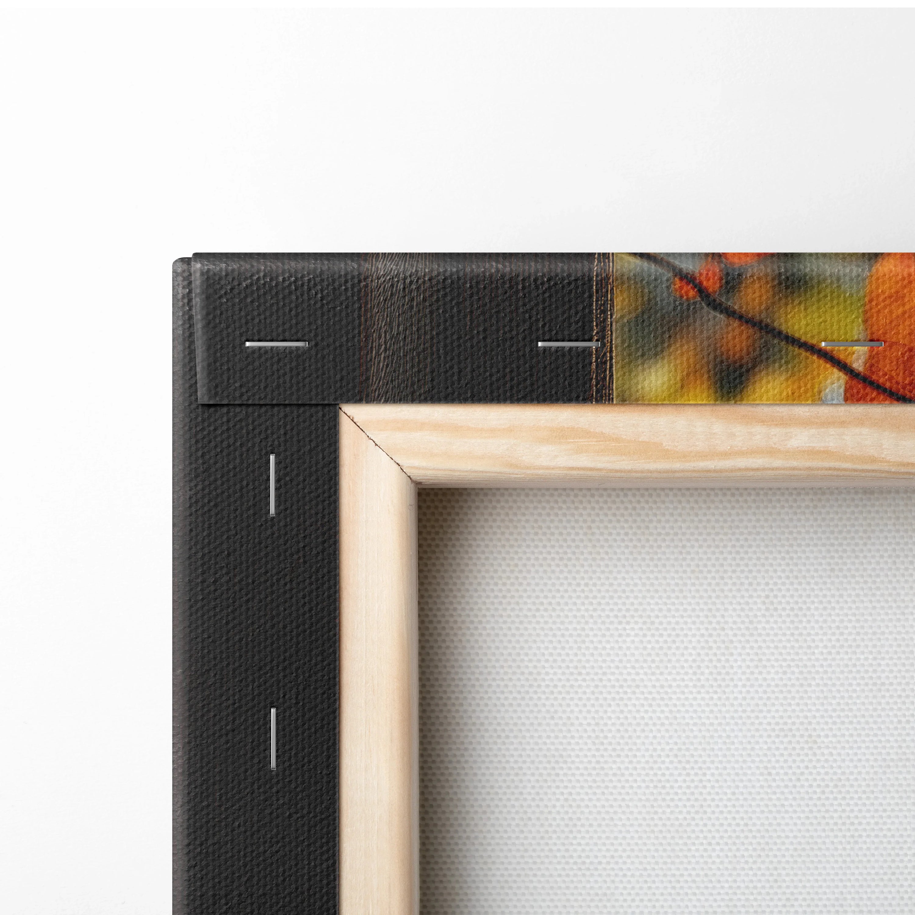 Close-up of wooden frame corner and black wrapped canvas edge with visible staple details on wall art.