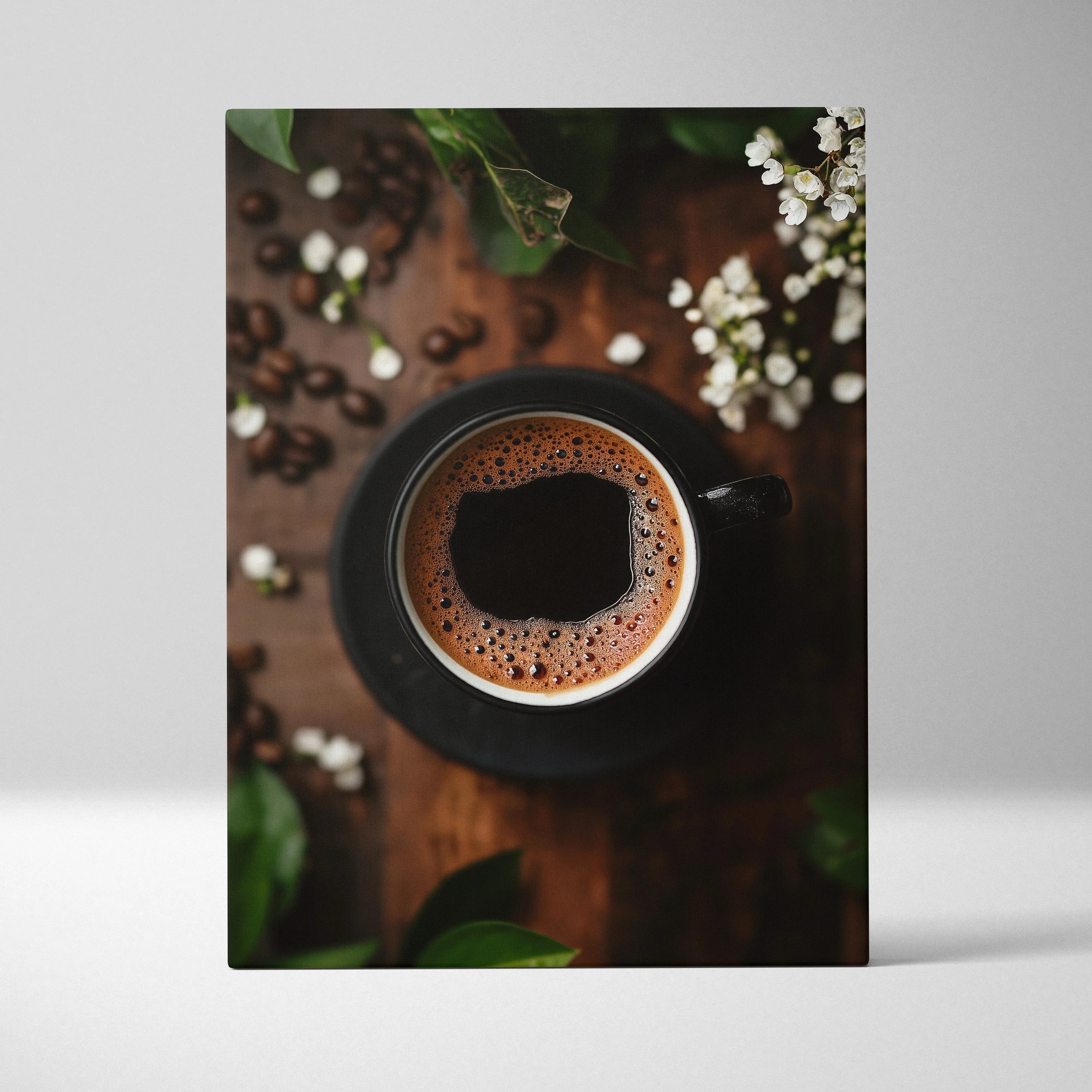 Vertical canvas wall art featuring a close-up top view of a coffee cup with foam and surrounding coffee beans and greenery.