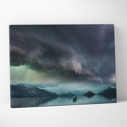 Rectangular canvas print of a lone sailboat on calm waters under dark storm clouds with distant snow-capped mountains wall decor