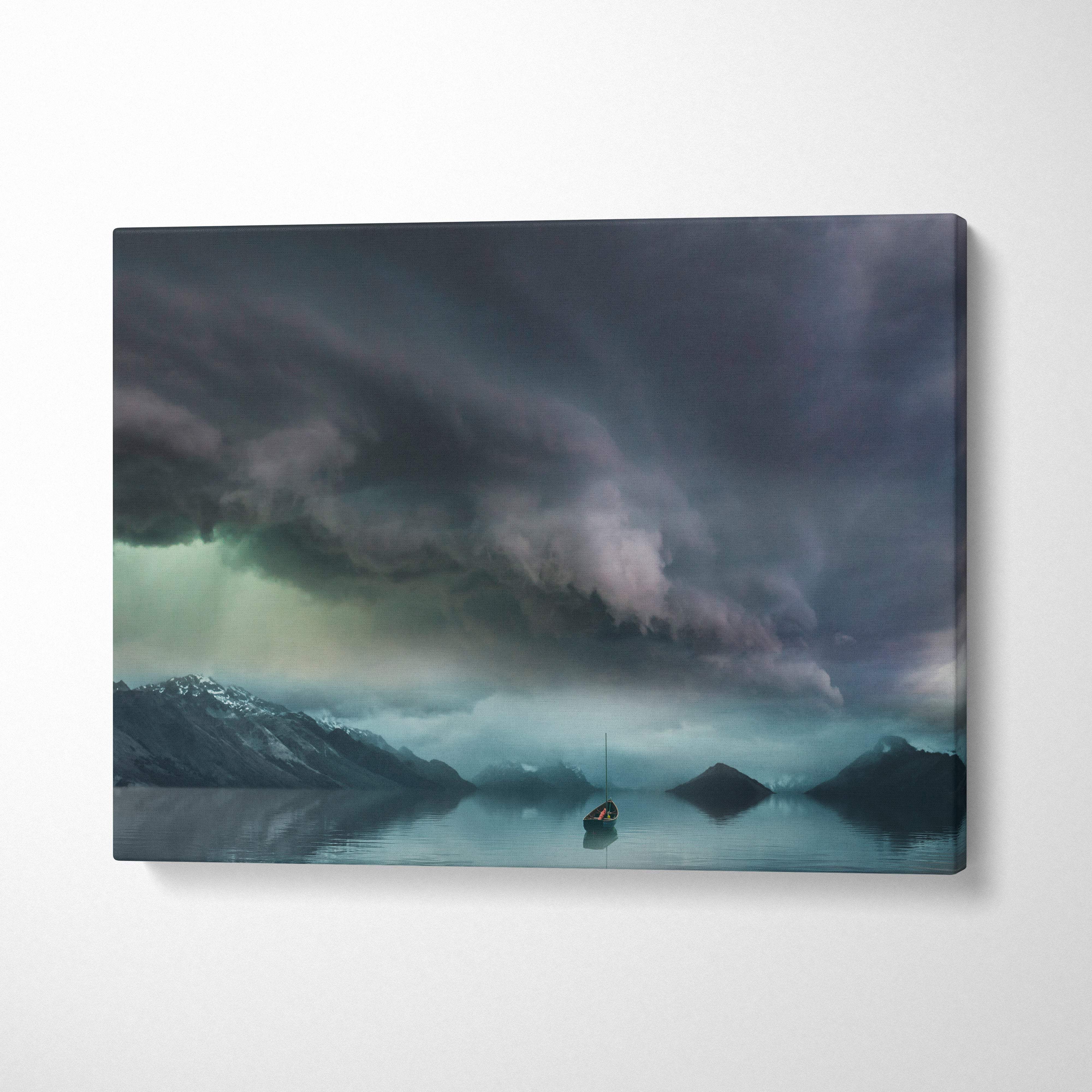 Rectangular canvas print of a moody sky with dark stormy clouds over snow-capped mountains and a lone sailboat on calm water