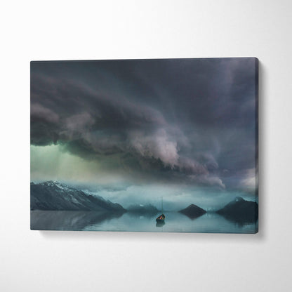 Rectangular canvas print of a moody sky with dark stormy clouds over snow-capped mountains and a lone sailboat on calm water