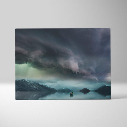 Rectangular canvas print of moody stormy sky with dark clouds over misty mountains and a lone sailboat on calm water