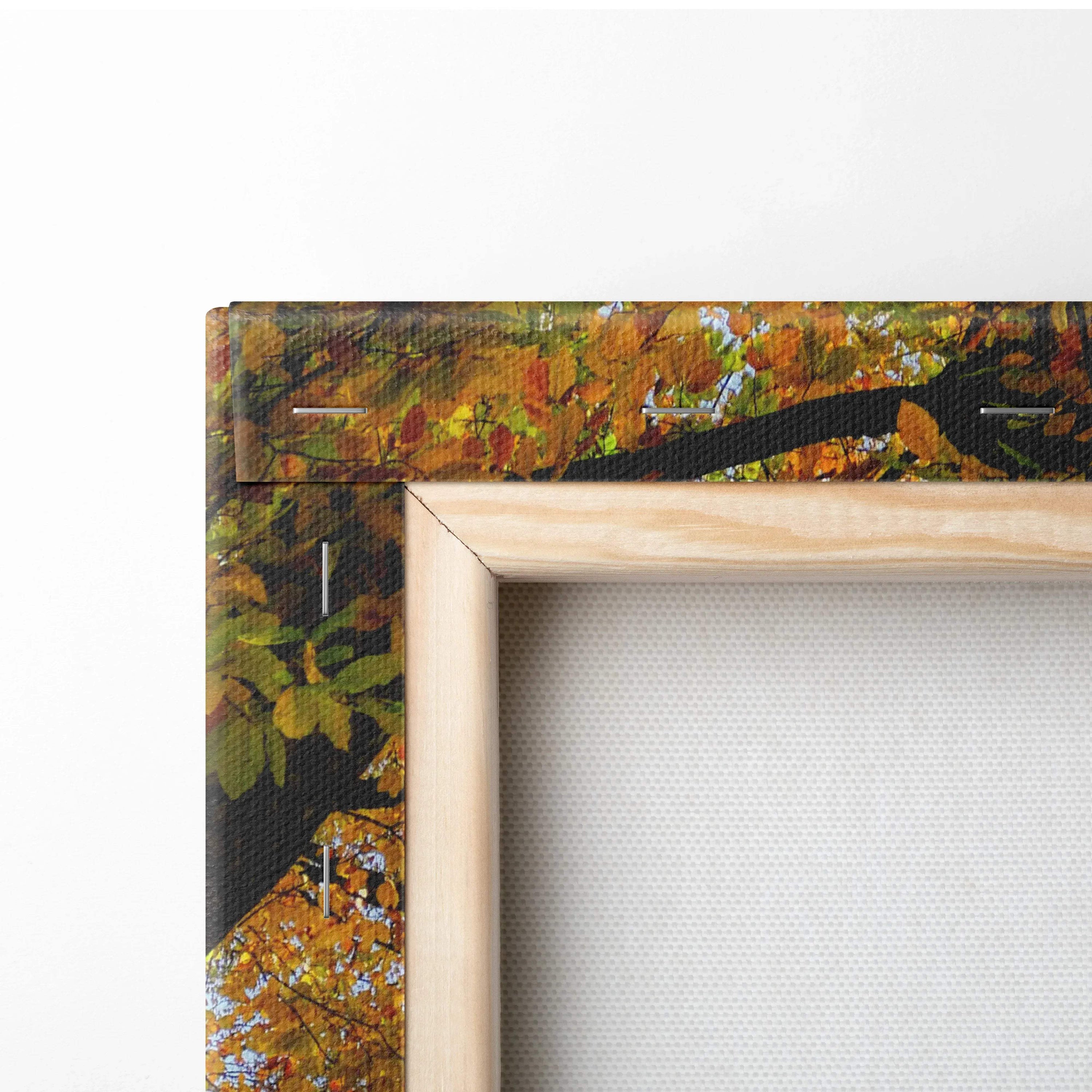 Close-up of wooden frame corner on vibrant autumn nature canvas wall art print with orange and green leaves.