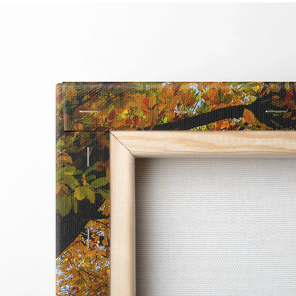 Close-up of wooden frame corner on vibrant autumn nature canvas wall art print with orange and green leaves.
