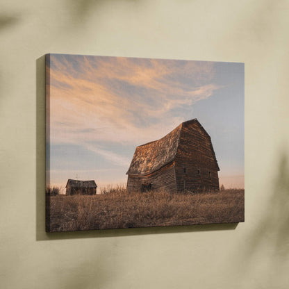 Canvas wall art featuring rustic wooden barns in a golden field under a soft sunset sky.