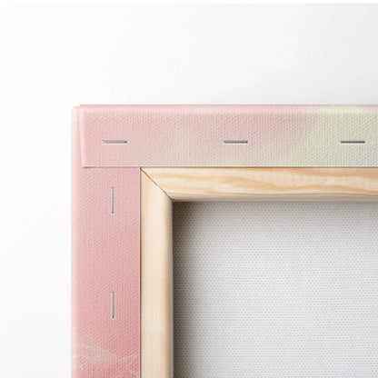 Close-up of canvas art corner showing light wood frame and soft pink abstract digital print.