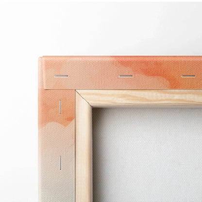 Close-up of stretched canvas with wooden frame and stapled corners, showing textured peach and orange abstract design.