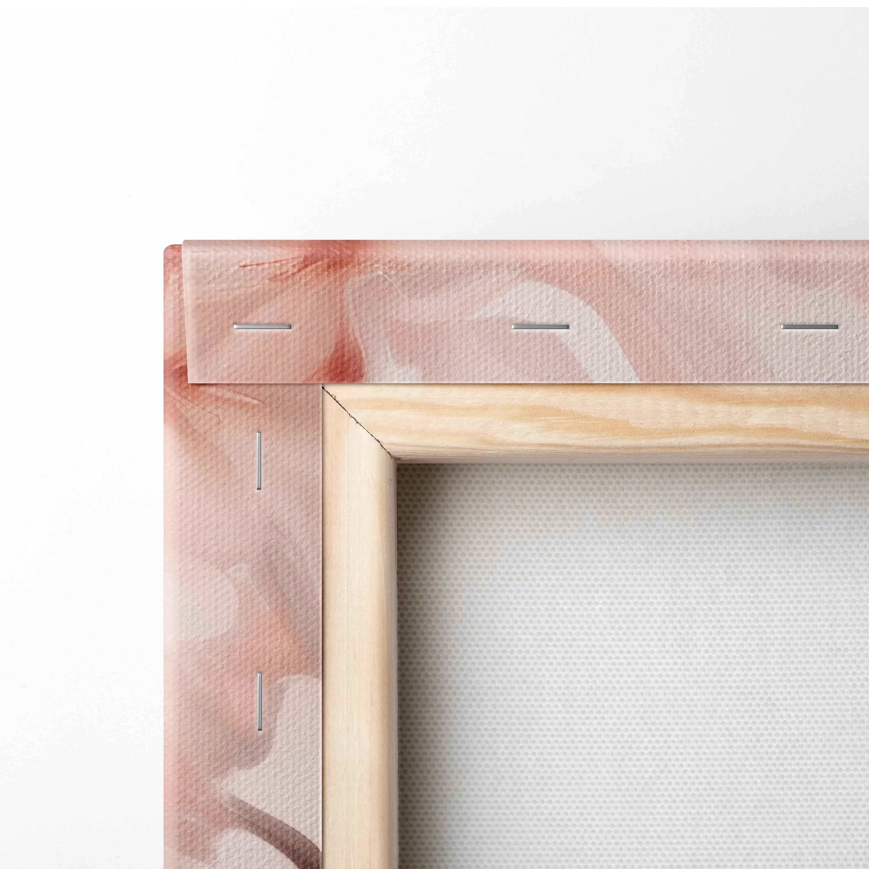 Close-up of wooden frame corner with stretched pink and peach abstract canvas art print.